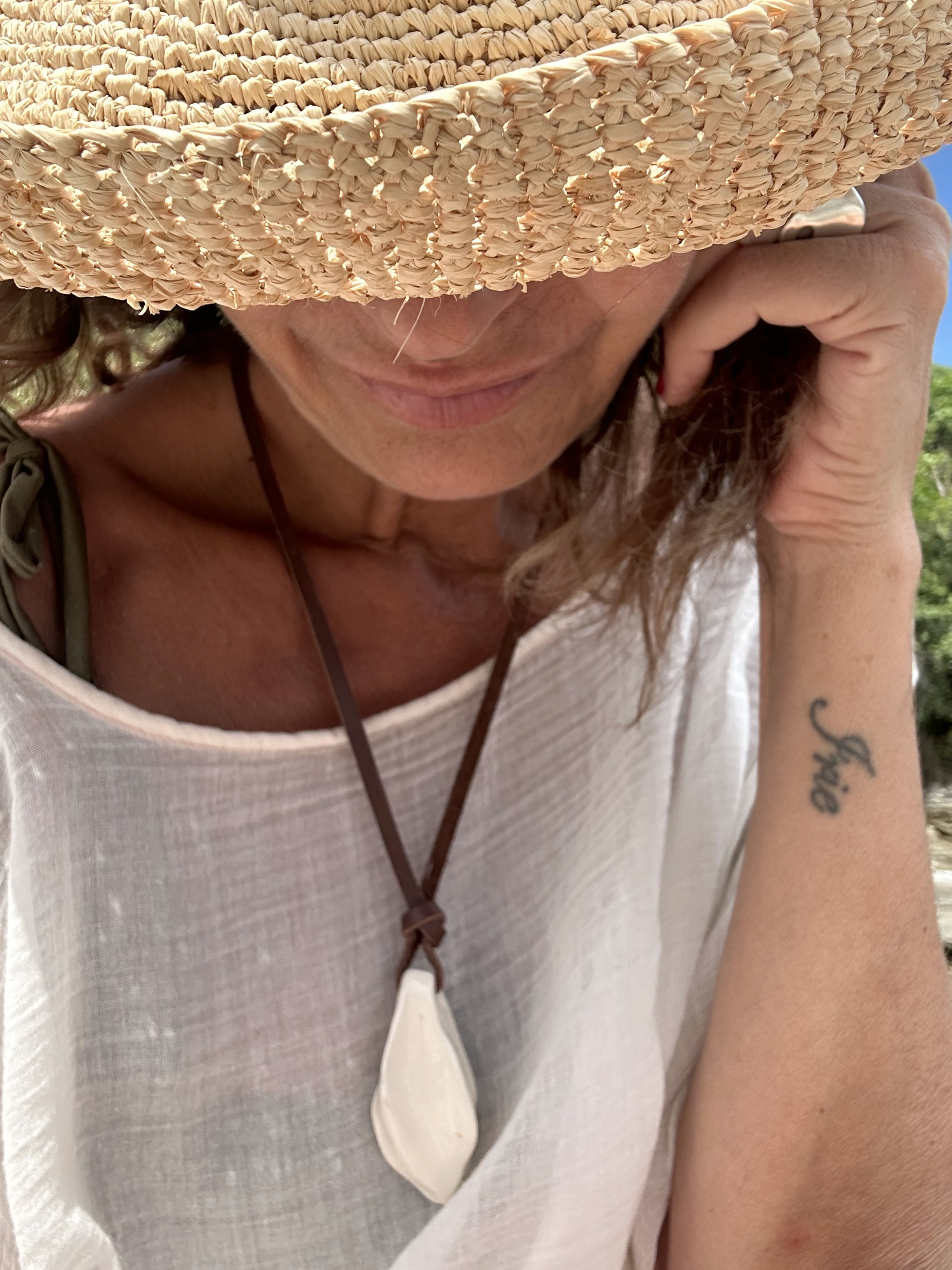 Close-up of pendant worn with straw hat and white blouse